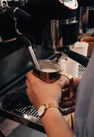 Barista schäumt Milch an der Espressomaschine auf