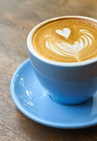 Latte mit Herz in einer blauen Tasse auf einem Holztisch